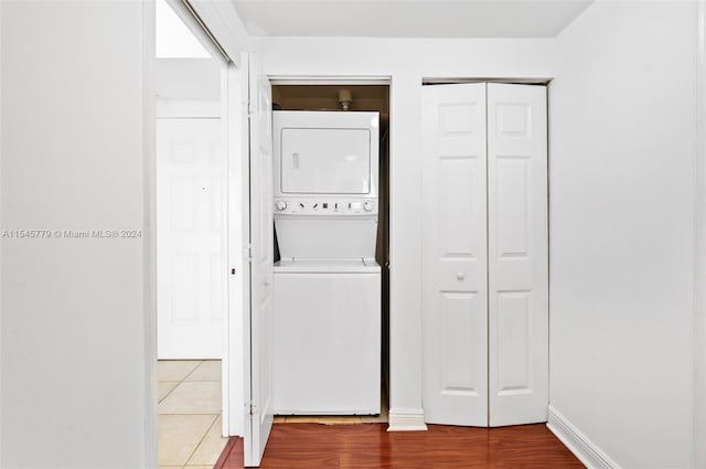 clothes washing area with hardwood / wood-style flooring and stacked washing maching and dryer