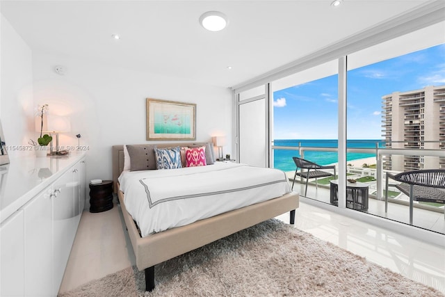 tiled bedroom featuring a water view, expansive windows, and access to outside