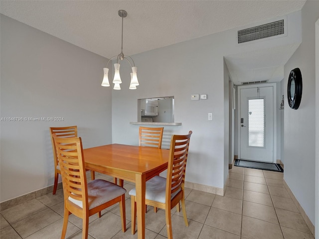 dining space featuring light tile flooring, a textured ceiling, and an inviting chandelier