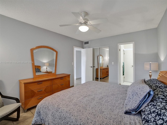 bedroom with a textured ceiling, ceiling fan, and light tile floors