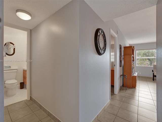 hallway featuring light tile floors and a textured ceiling