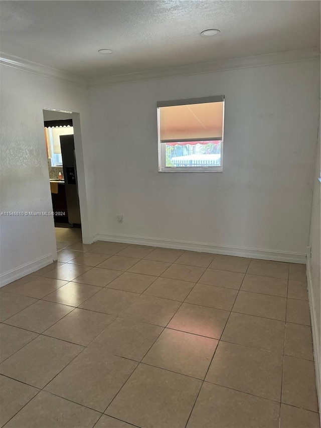 tiled empty room featuring ornamental molding