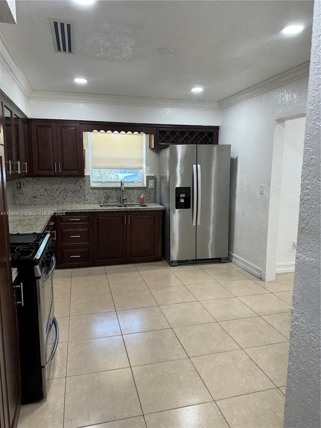 kitchen featuring sink, black range with gas stovetop, light stone counters, stainless steel fridge, and crown molding