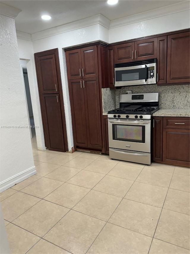 kitchen featuring stainless steel appliances, light stone counters, crown molding, decorative backsplash, and light tile patterned flooring