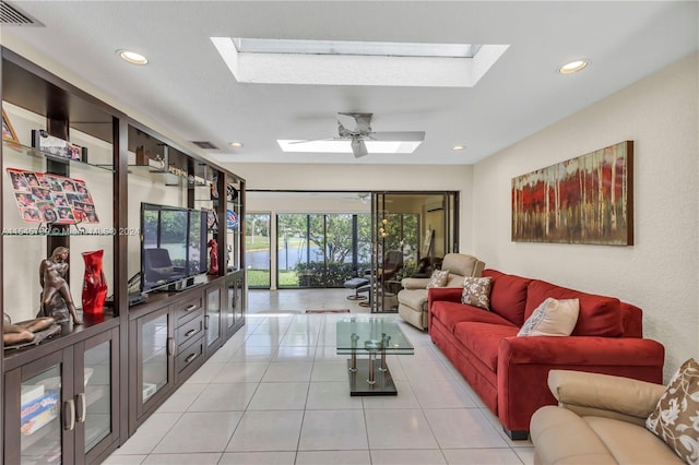 living room featuring a skylight, ceiling fan, and light tile floors