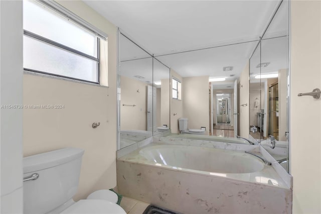 bathroom with a relaxing tiled bath, tile floors, and toilet