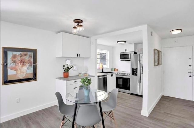 kitchen featuring stainless steel appliances, sink, white cabinetry, and light wood-type flooring