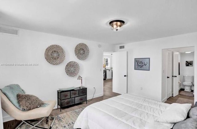 bedroom with ensuite bath and hardwood / wood-style flooring