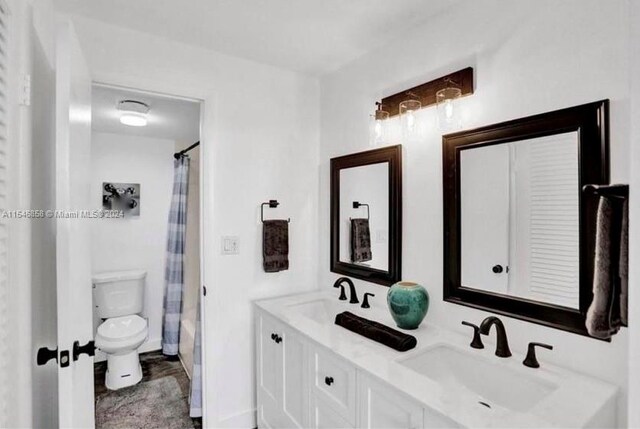 bathroom featuring toilet, dual sinks, and large vanity