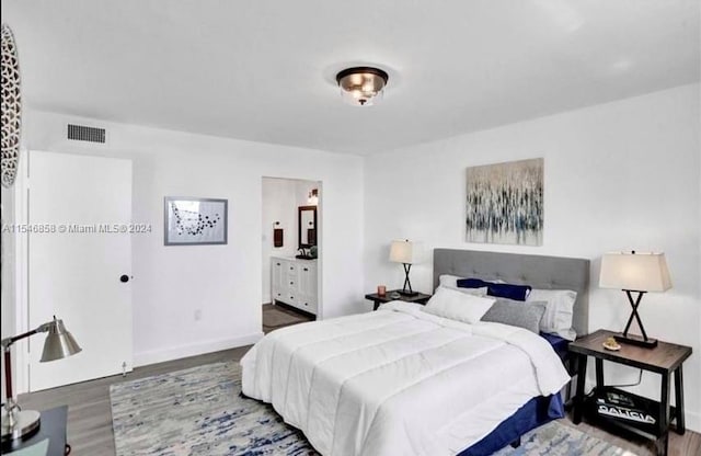 bedroom featuring connected bathroom and dark hardwood / wood-style floors