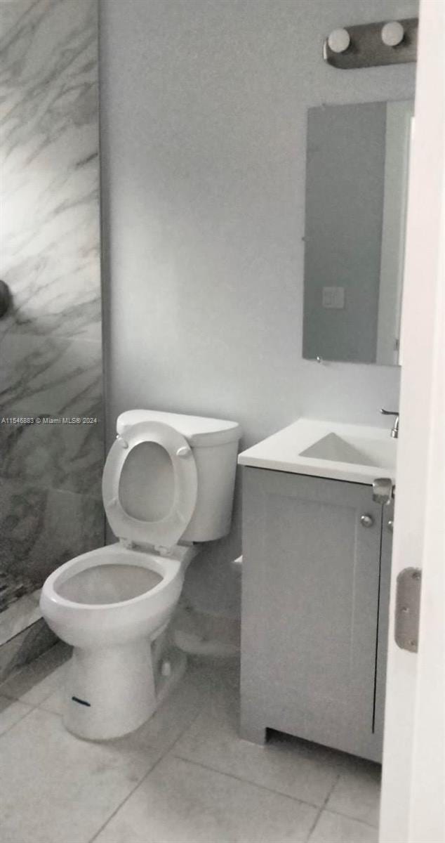 bathroom featuring toilet, vanity, and tile flooring