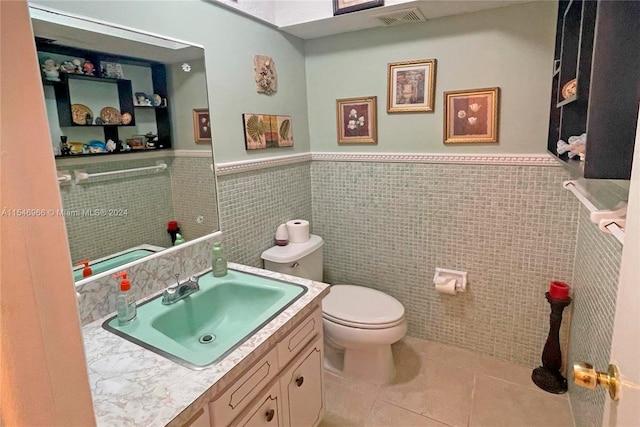 bathroom with tile walls, tile patterned flooring, toilet, and vanity