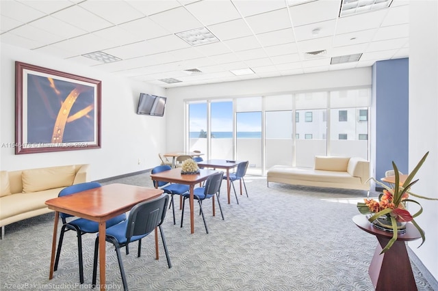 dining area featuring a paneled ceiling, a water view, and carpet