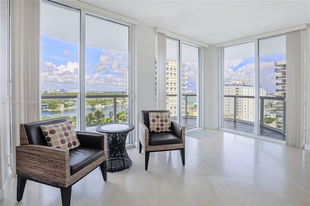 sitting room with a water view, light tile floors, and a wall of windows