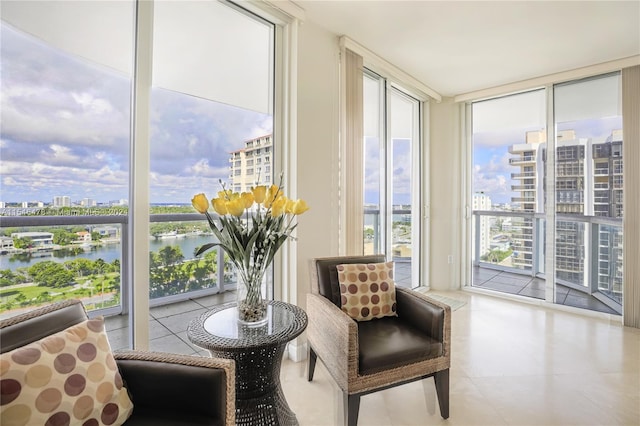 sitting room with a healthy amount of sunlight, expansive windows, light tile floors, and a water view