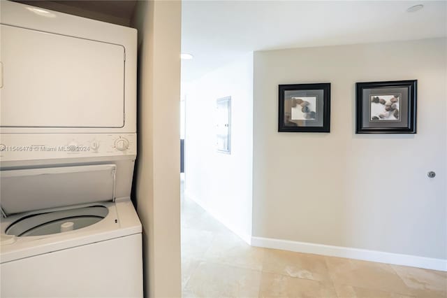 laundry area featuring light tile floors and stacked washer / dryer