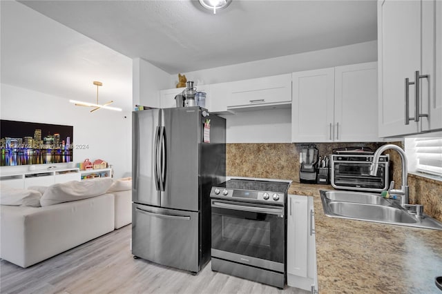 kitchen featuring a notable chandelier, tasteful backsplash, appliances with stainless steel finishes, white cabinetry, and light wood-type flooring