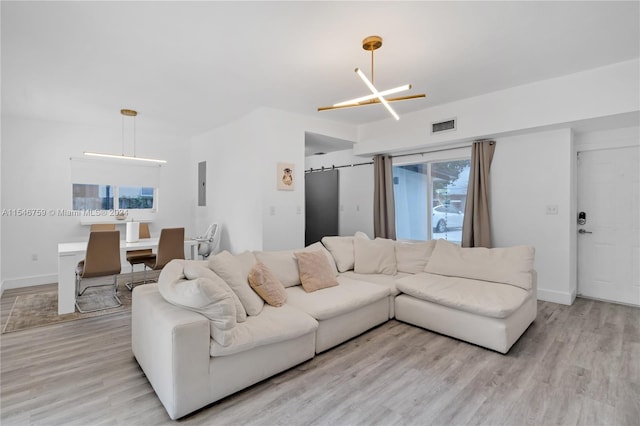 living room featuring a chandelier, a healthy amount of sunlight, and light hardwood / wood-style flooring