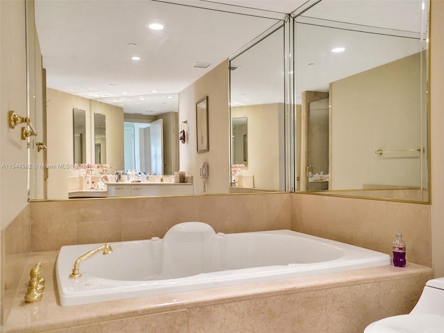 bathroom with oversized vanity and tiled tub