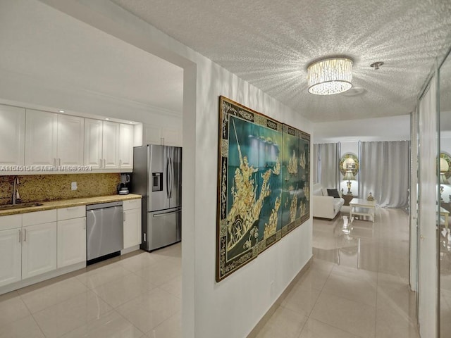 kitchen with white cabinets, appliances with stainless steel finishes, light tile floors, and sink