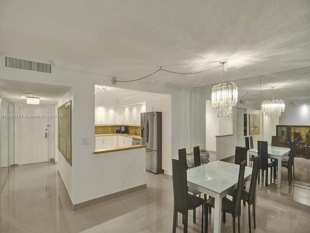 dining area featuring light tile flooring, a textured ceiling, and an inviting chandelier