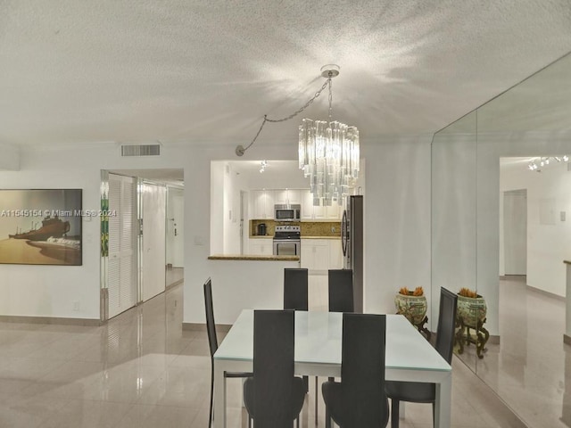 dining area featuring a chandelier, light tile flooring, and a textured ceiling