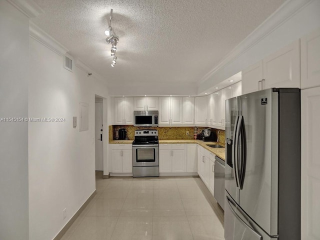 kitchen featuring a textured ceiling, ornamental molding, white cabinetry, appliances with stainless steel finishes, and track lighting