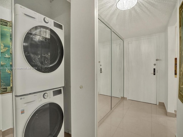 laundry room featuring stacked washing maching and dryer, light tile floors, and a textured ceiling