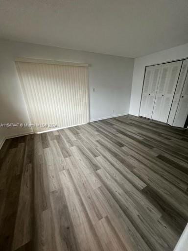 unfurnished bedroom featuring a closet and dark hardwood / wood-style flooring