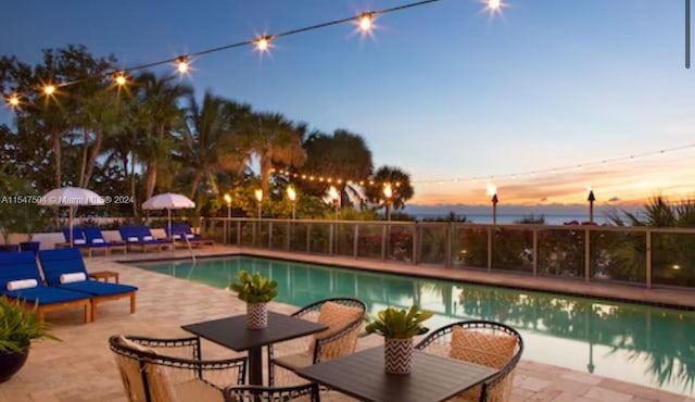 pool at dusk featuring a patio