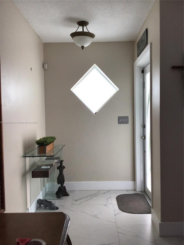 tiled foyer featuring plenty of natural light and a textured ceiling