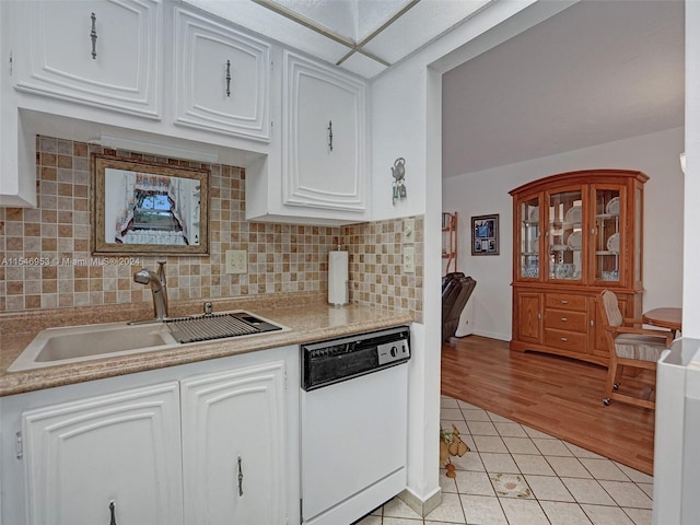 kitchen with backsplash, light hardwood / wood-style floors, sink, white cabinets, and white dishwasher