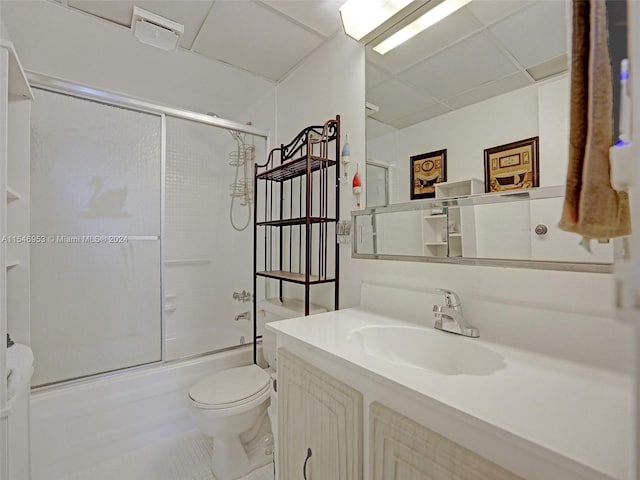 full bathroom featuring toilet, enclosed tub / shower combo, a drop ceiling, tile flooring, and vanity