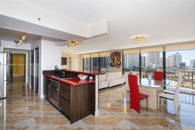 kitchen featuring light tile floors, a wall of windows, dark brown cabinets, and stainless steel appliances