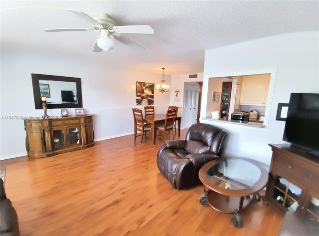 living room with ceiling fan with notable chandelier, a textured ceiling, and hardwood / wood-style flooring