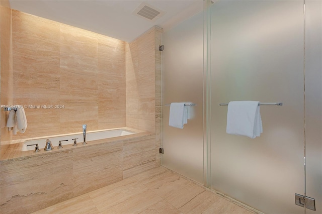 bathroom with tiled tub and tile flooring