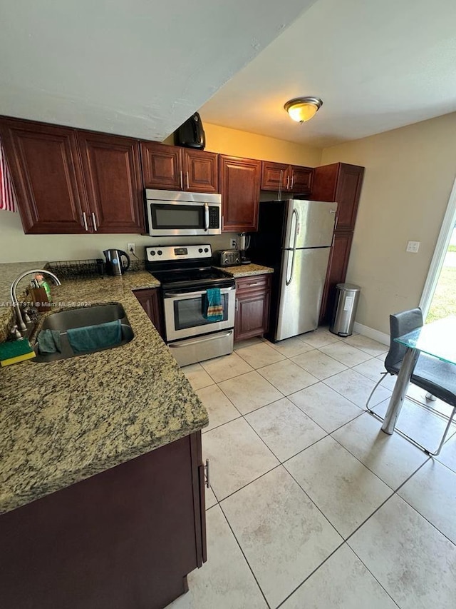 kitchen with light stone counters, appliances with stainless steel finishes, sink, and light tile flooring