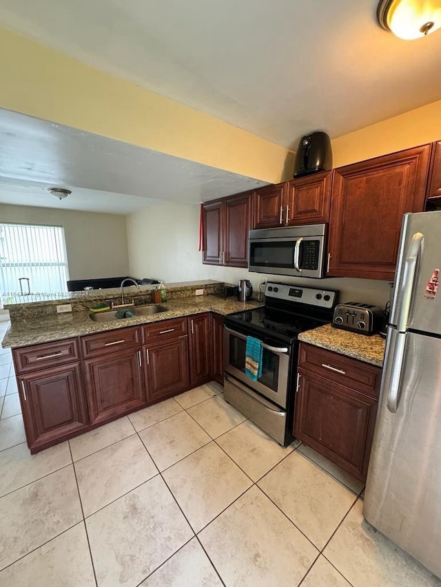 kitchen with appliances with stainless steel finishes, kitchen peninsula, stone counters, sink, and light tile floors