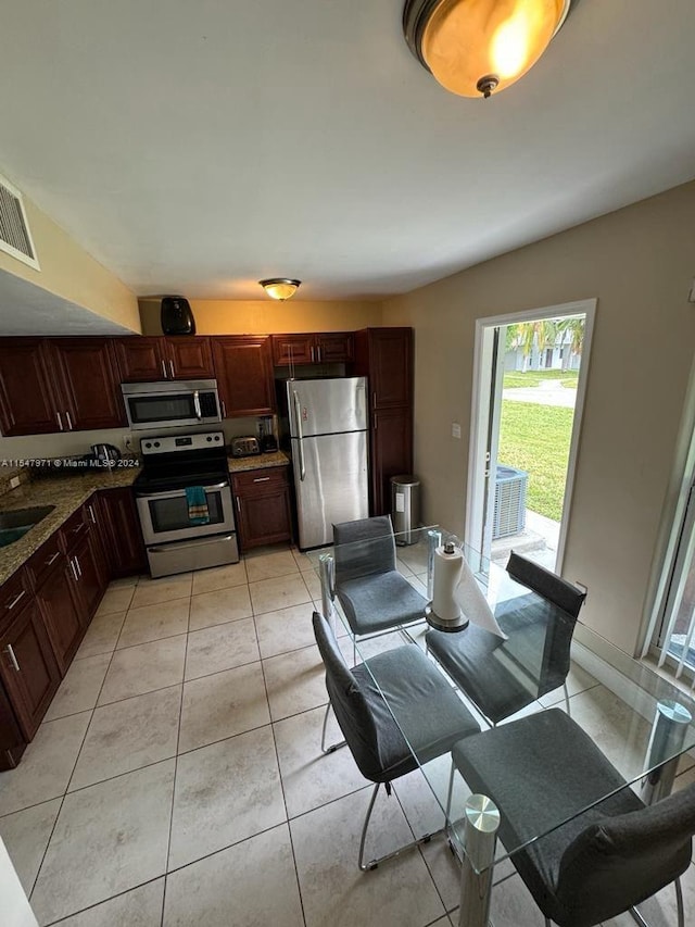 kitchen featuring stainless steel appliances, stone counters, light tile flooring, and sink