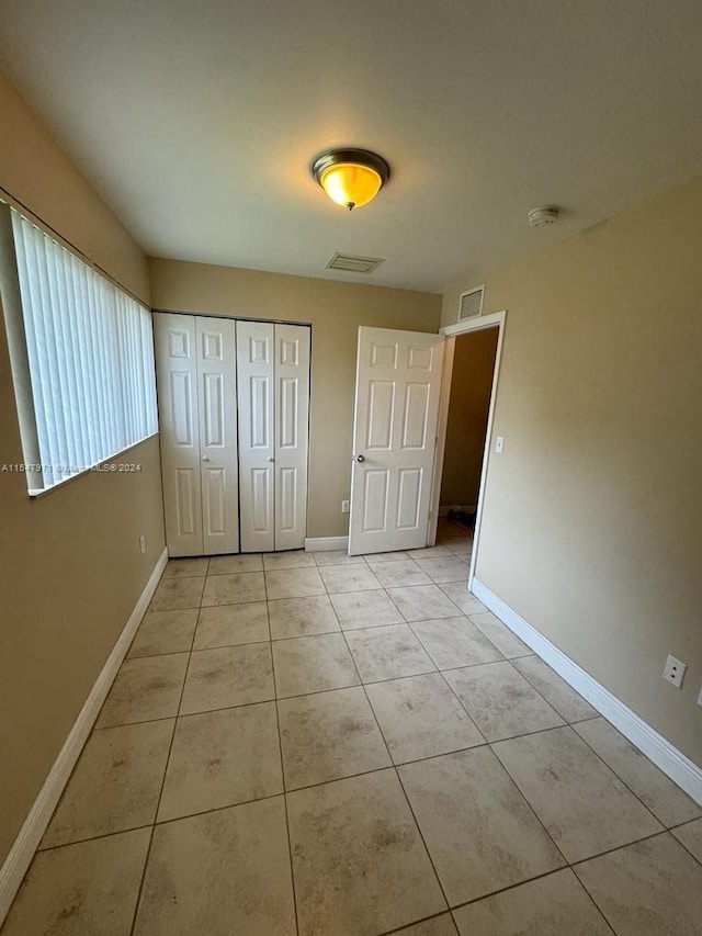 unfurnished bedroom with a closet and light tile floors