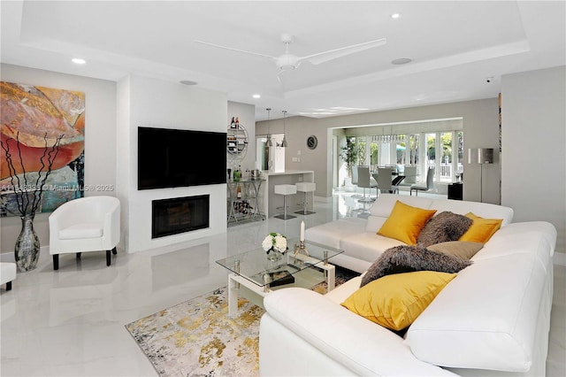 living room with ceiling fan and a tray ceiling