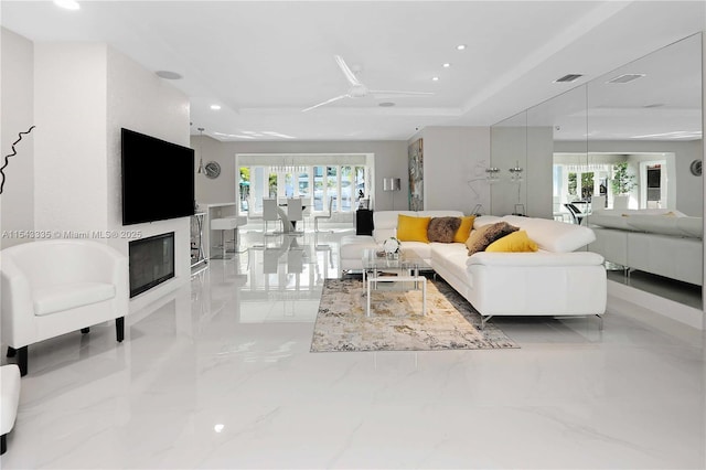 living room with ceiling fan and a raised ceiling