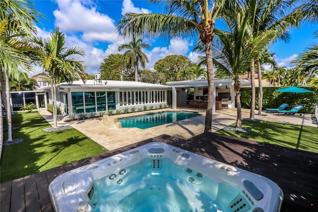 view of pool with exterior bar, an outdoor hot tub, a lawn, and a patio