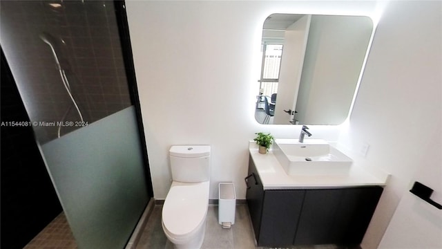 bathroom with vanity, tiled shower, and toilet