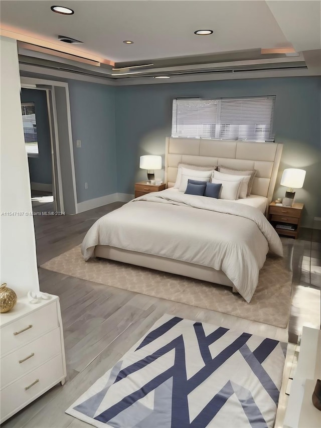 bedroom featuring light hardwood / wood-style floors and a raised ceiling