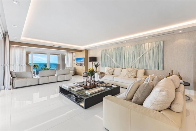 living room with a tray ceiling and light tile flooring