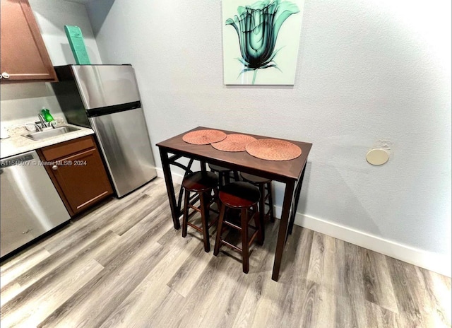 kitchen with stainless steel appliances, sink, and light wood-type flooring