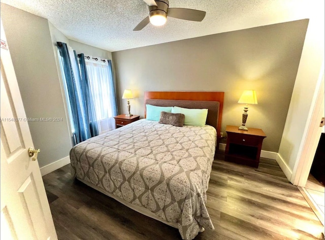 bedroom with a textured ceiling, ceiling fan, and dark wood-type flooring