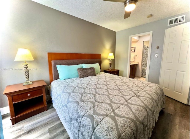 bedroom featuring ceiling fan, connected bathroom, light hardwood / wood-style flooring, and a textured ceiling