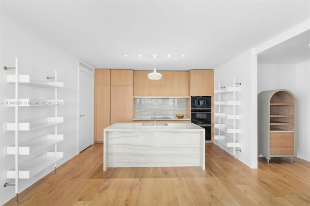 kitchen with sink, light hardwood / wood-style flooring, decorative backsplash, black appliances, and light stone countertops